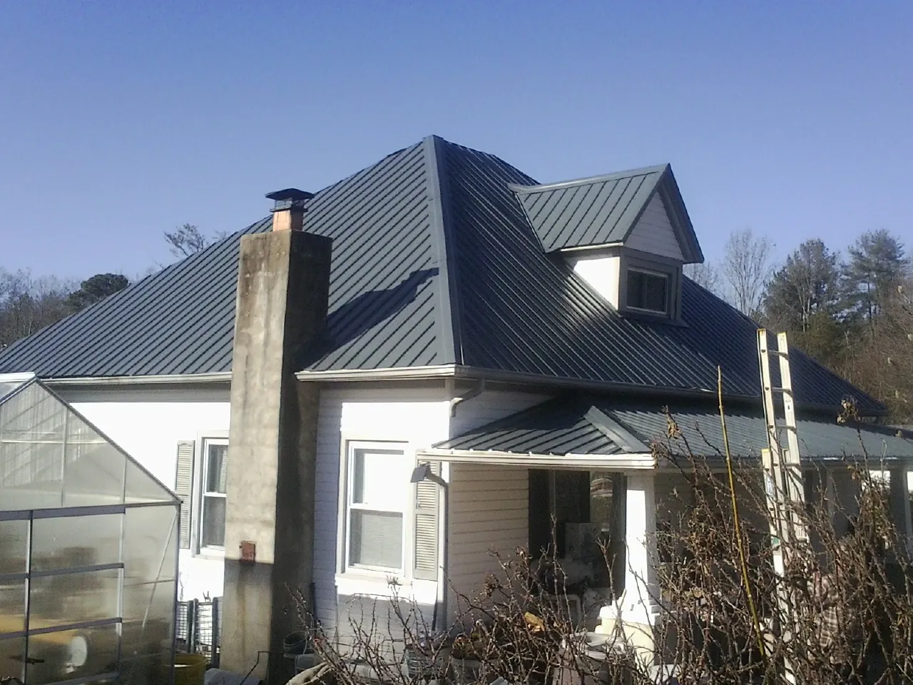 Dark blue standing seam metal roof on a white farmhouse with dormer — Slate & Tile Roof Repair by Roofing Brothers in Garnet Valley