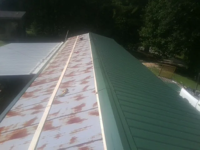Old rusted panels beside newly installed green metal roofing — Wind Damage Roof Repair by Roofing Brothers in Garnet Valley