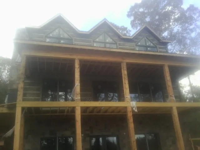 Dormers and porch framing on a large log home under construction — Roof Coating work by our crew in Garnet Valley