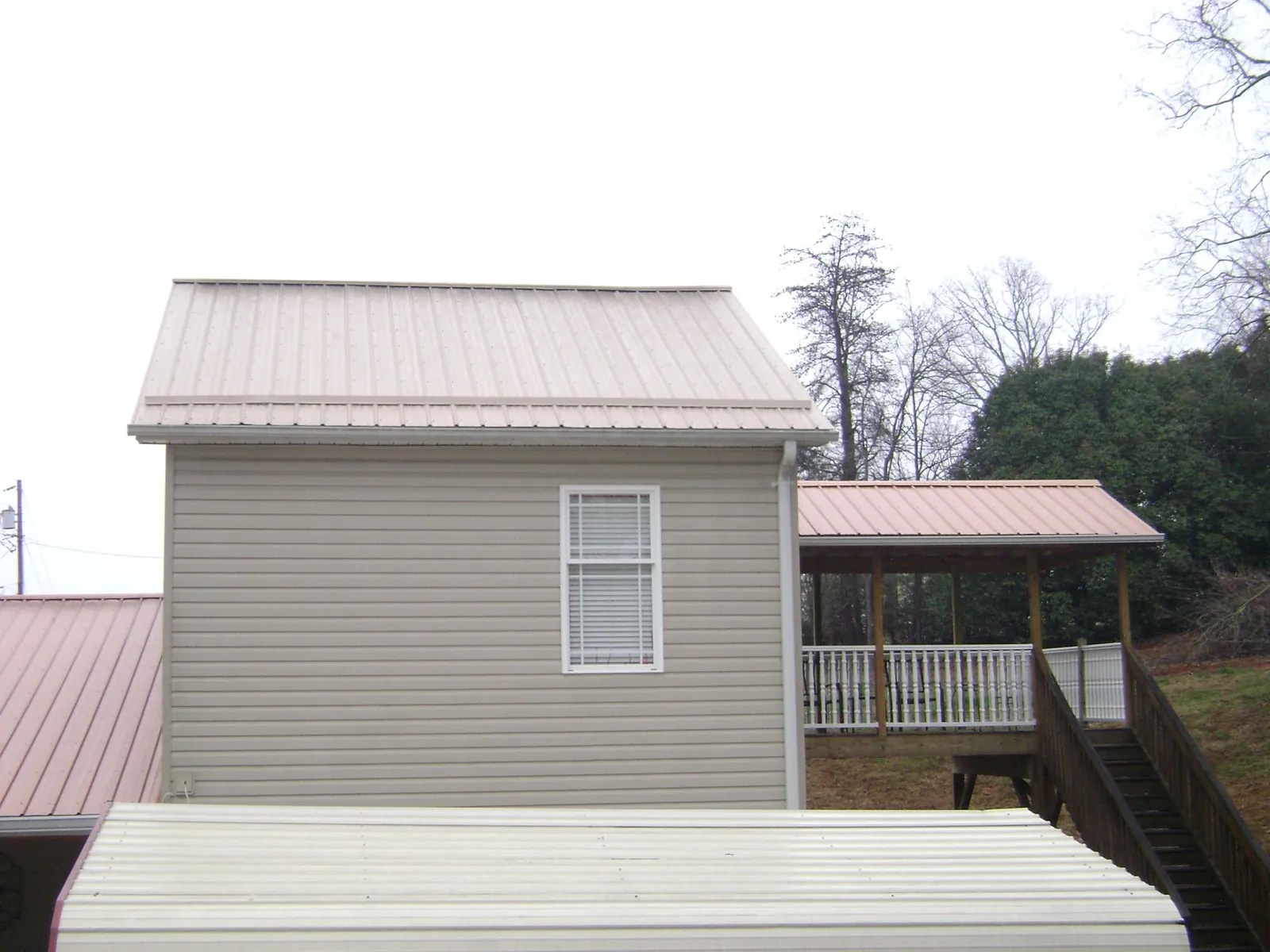 Tan metal roofs on a two story addition and attached porch, from a Roof Replacement job in Garnet Valley