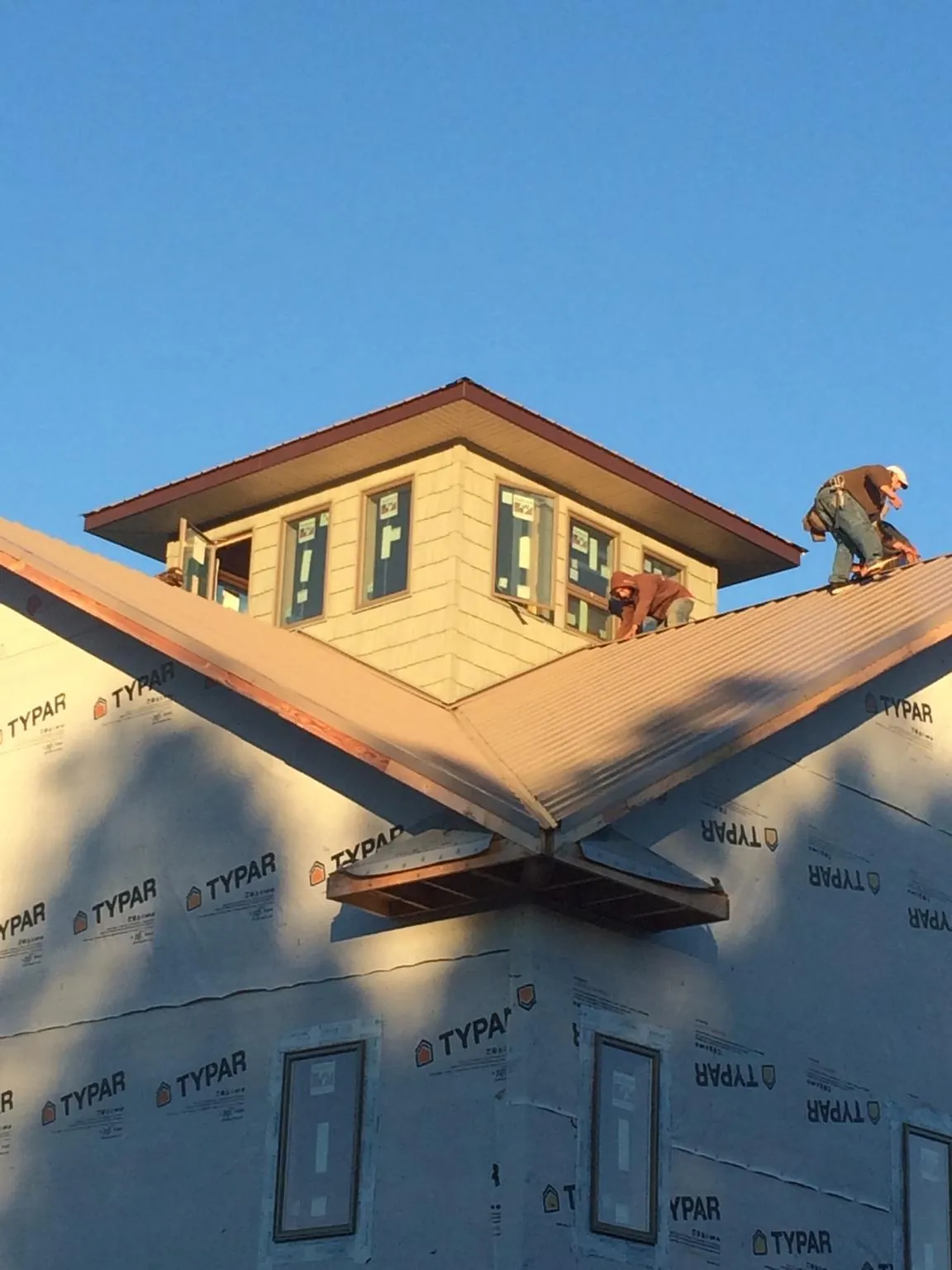 Roofers working around a rooftop cupola on a new metal roof at sunset — Roof Waterproofing in Garnet Valley by Roofing Brothers